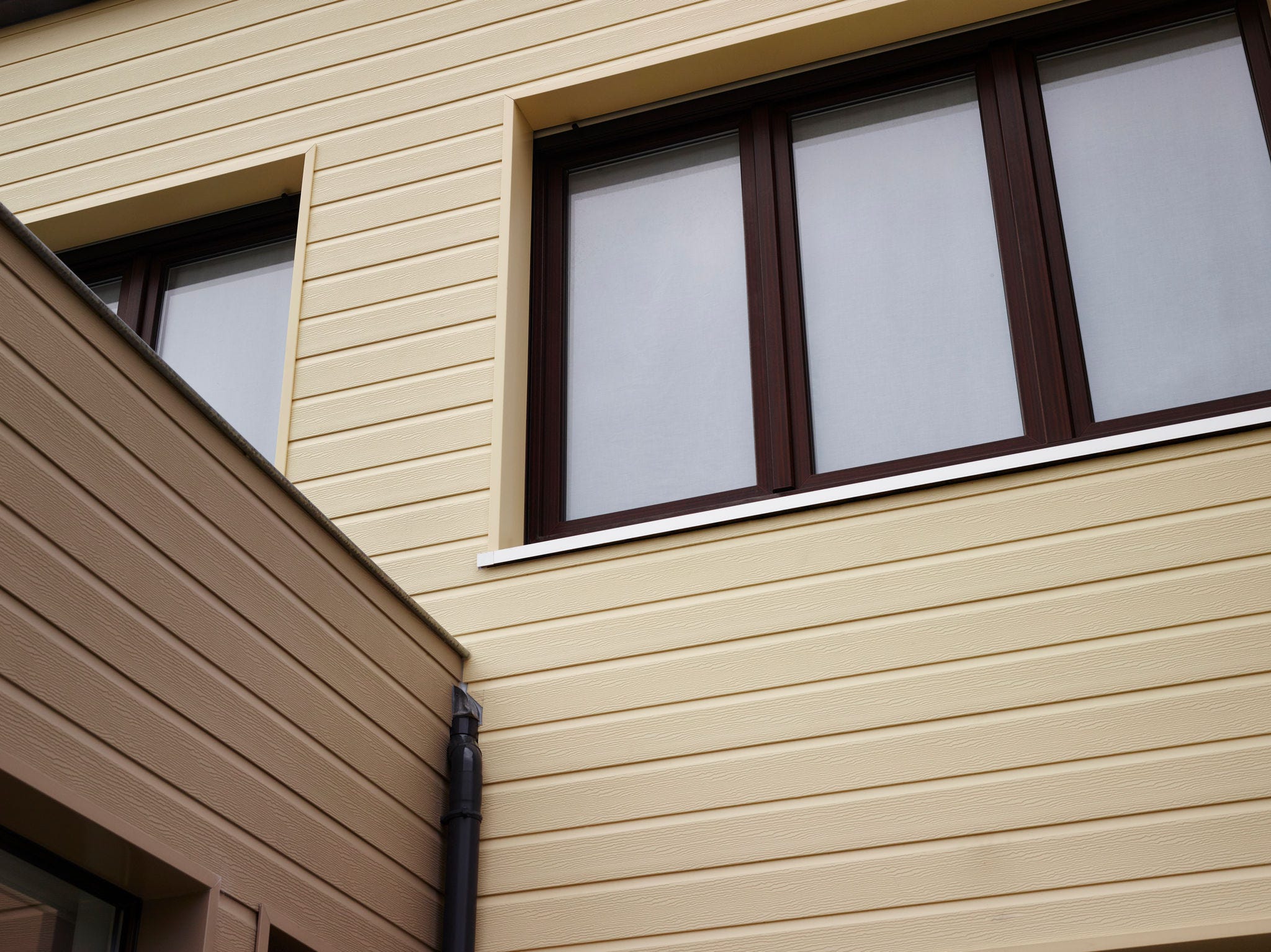 Deceuninck Solid Pure Fassadenverkleidung in Cremeweiß mit Holzmaserung an einem Wohnhaus